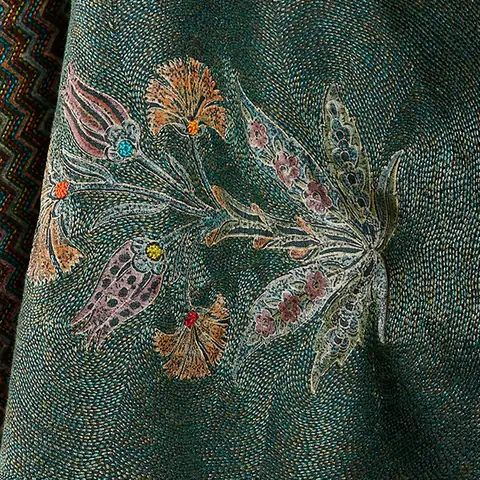 A Kantha textile, dense running stitches filling a teal ground and building floral motifs in soft natural colors.